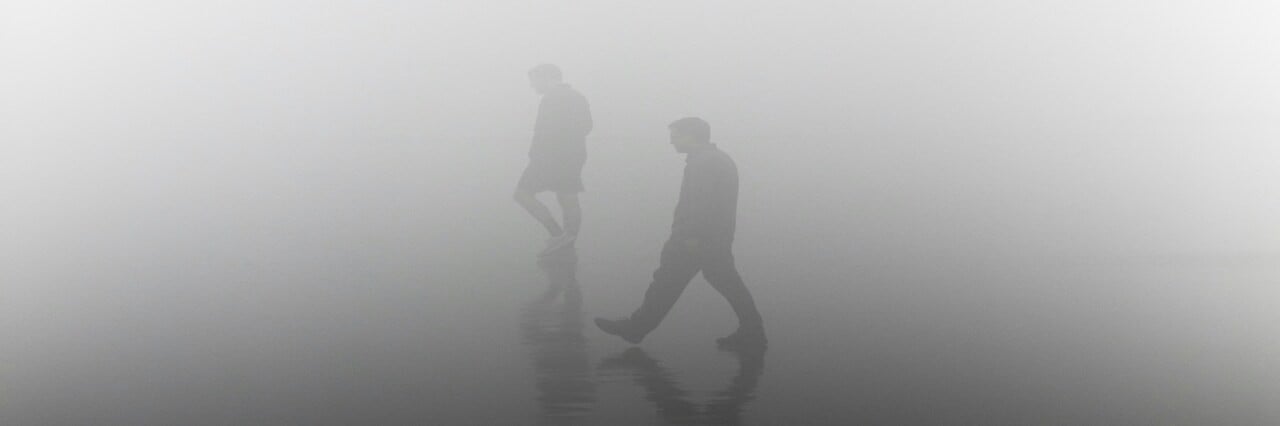 Deux hommes marchent dans le brouillard