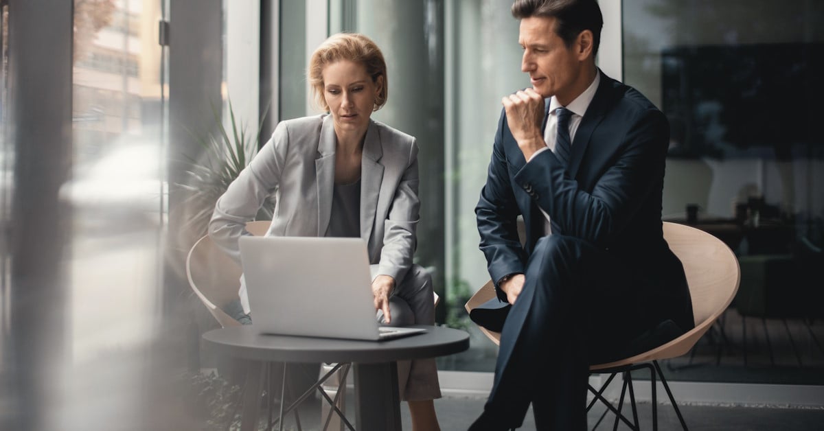 Deux personnes qui discutent autour d'une table, face à un ordinateur